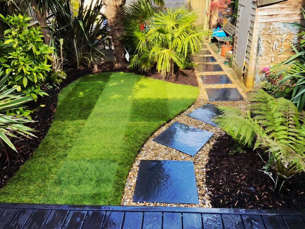 An image of a Gloss 'n' Gardens project done for a client. There is new sod laid out in the yard, and a new stone patio that leads to the house.