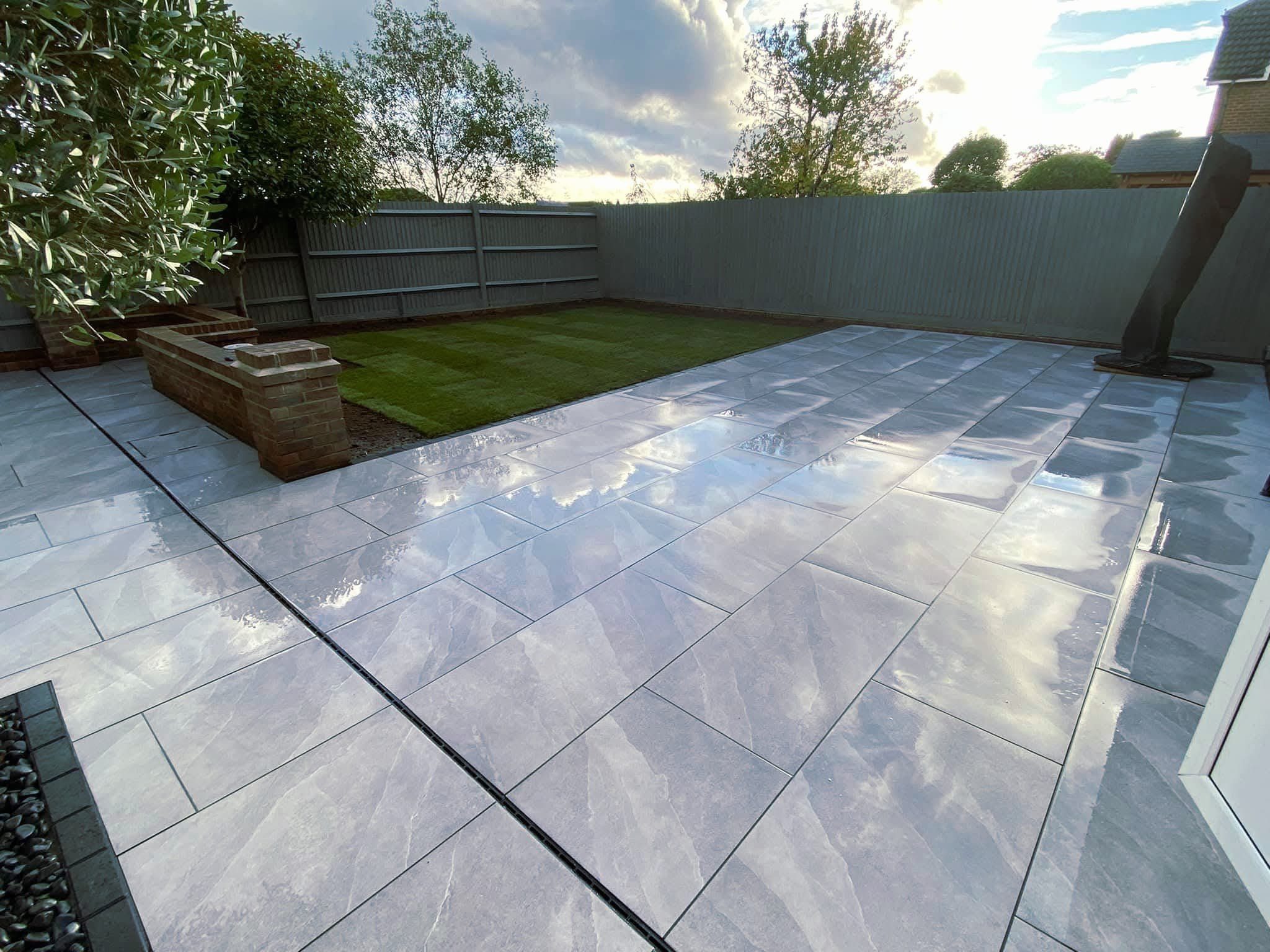 An image of a Gloss 'n' Gardens project done for a client. There is new sod laid out in the yard, and a new stone patio.