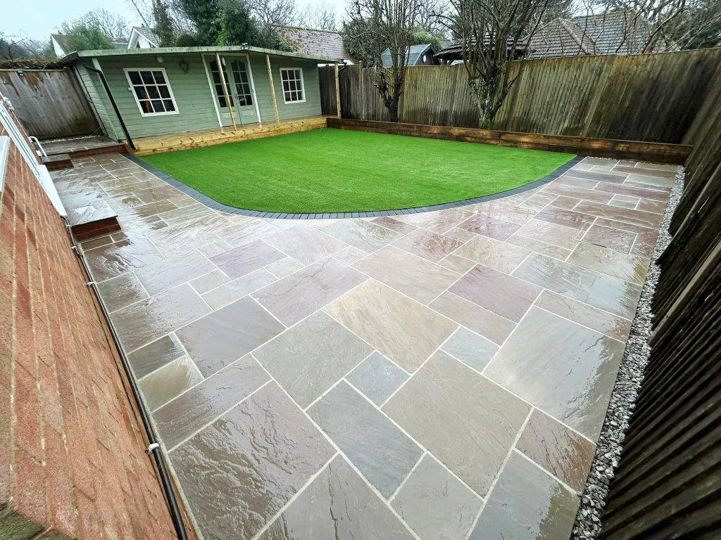 An image of a Gloss 'n' Gardens project done for a client. There is new sod laid out in the yard, and a new stone patio that leads to the house.