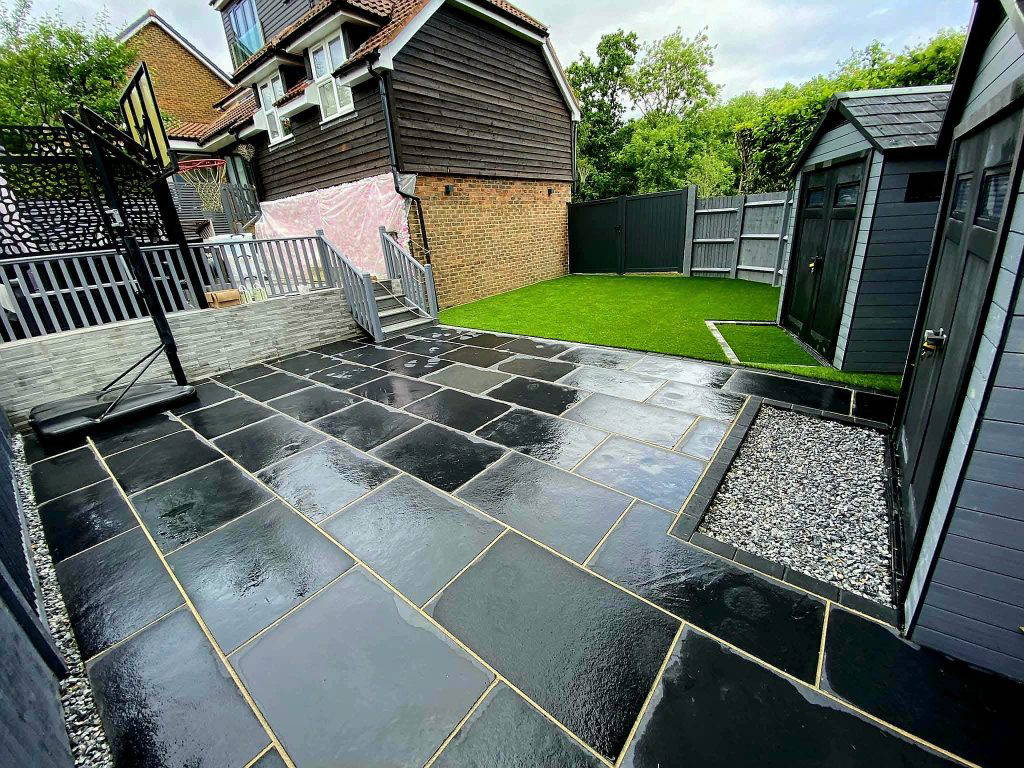 An image of a Gloss 'n' Gardens project done for a client. There is turf laid out in the yard, and a new stone patio that leads to the house.