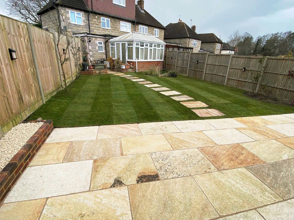 An image of a Gloss 'n' Gardens project done for a client. There is new sod laid out in the yard, and a new stone patio that leads to the house.